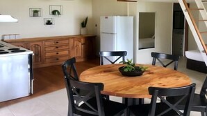 A kitchen with wooden cabinets, a stove, and a dining area with a round table and chairs.