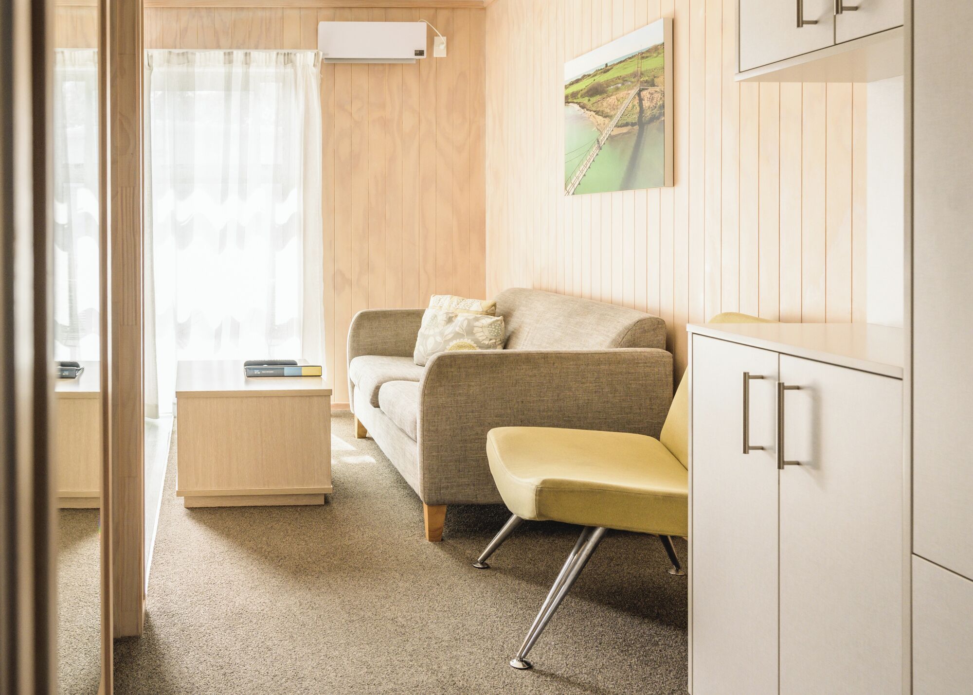 Ein modernes Wohnzimmer mit einer Couch, einem kleinen Tisch und einem Schrank.