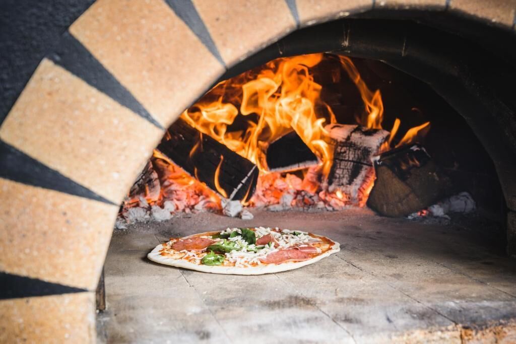 Pizza em forno de tijolos com chamas.