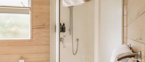 A modern bathroom with a glass shower enclosure, a toilet, and a towel rack.