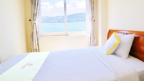 A hotel room with a bed, a window with curtains, and a view of the sea. - Hoang Yen Canary Hotel (Quy Nhon)