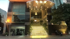 The exterior of Hoang Yen Canary Hotel with a prominent illuminated sign, a modern glass facade, and a staircase leading to the entrance. - Hoang Yen Canary Hotel (Quy Nhon)