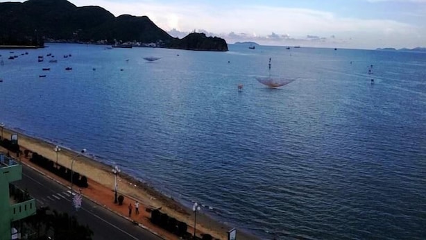 A coastal view with a road parallel to the water, boats, and distant mountains. - Hoang Yen Canary Hotel (Quy Nhon)