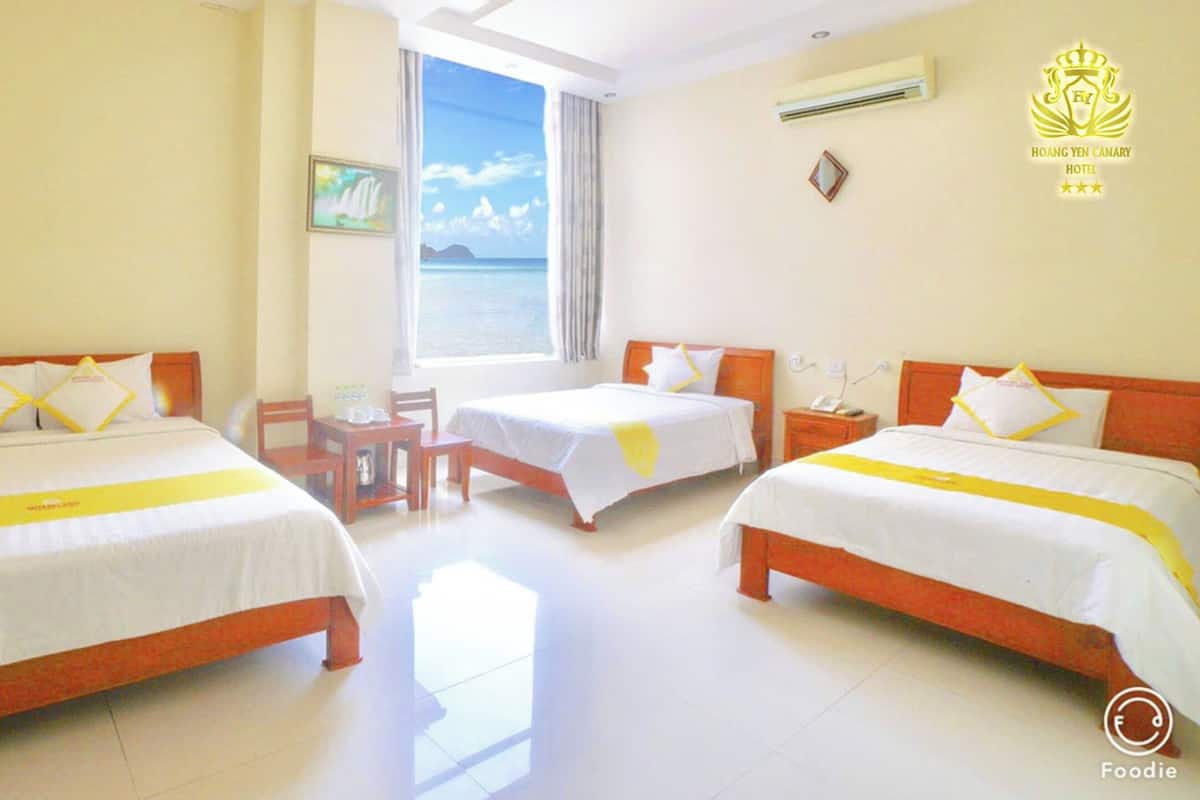 Une chambre d’hôtel avec deux lits, une petite table et une fenêtre donnant sur la mer.