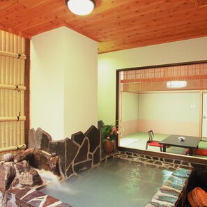 A hot spring area with a stone wall, a wooden ceiling, and a table with chairs. - Hot Springs Inn 'unzen Iwaki Ryokan' (Unzen)