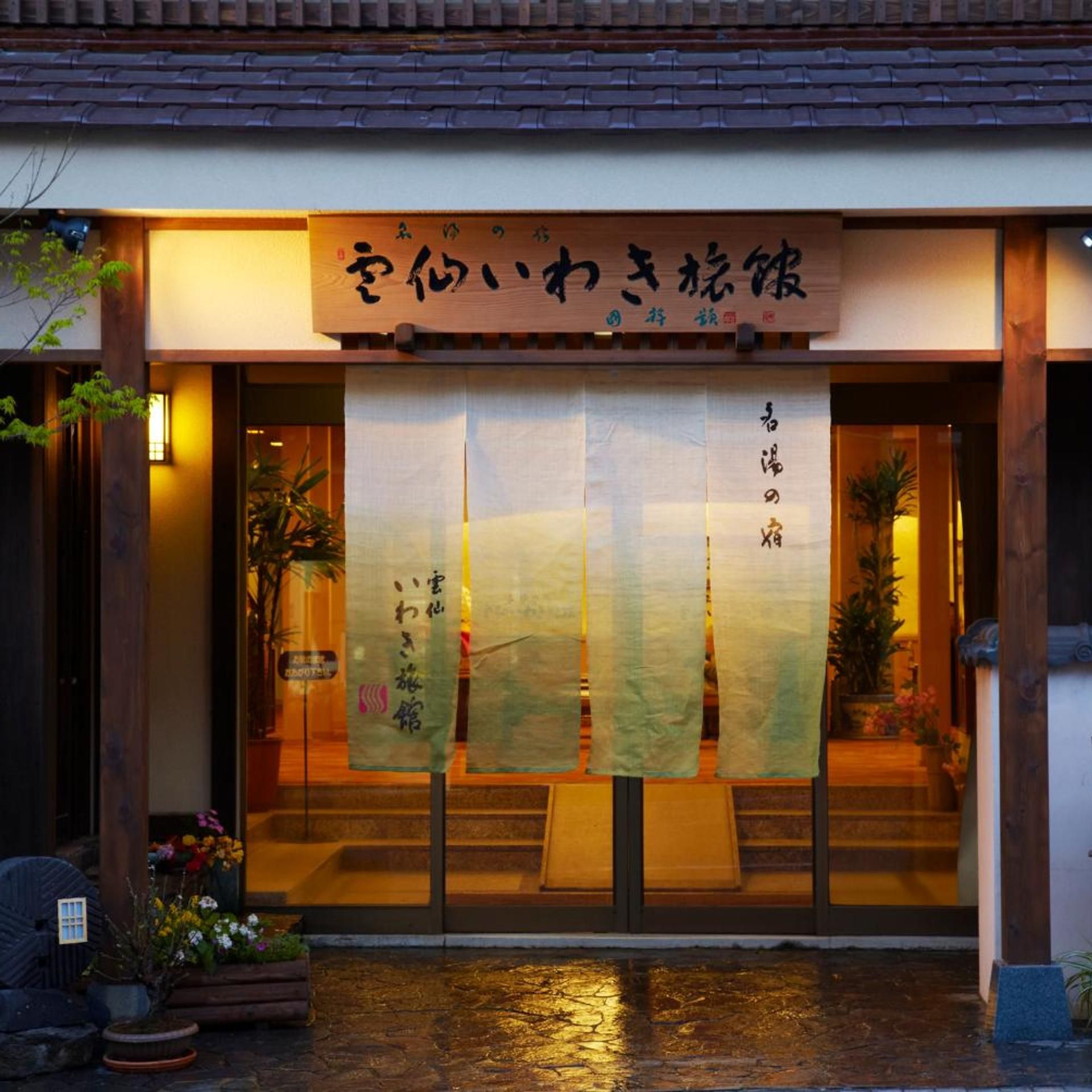 A traditional Japanese establishment with a wooden signboard and a sliding door entrance.