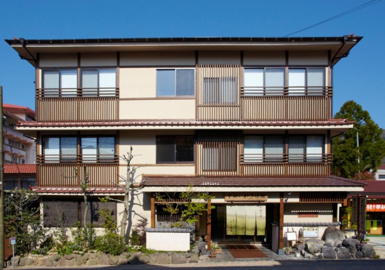 Un edificio de dos pisos con estilo arquitectónico japonés tradicional, con balcones de madera y techo de tejas.