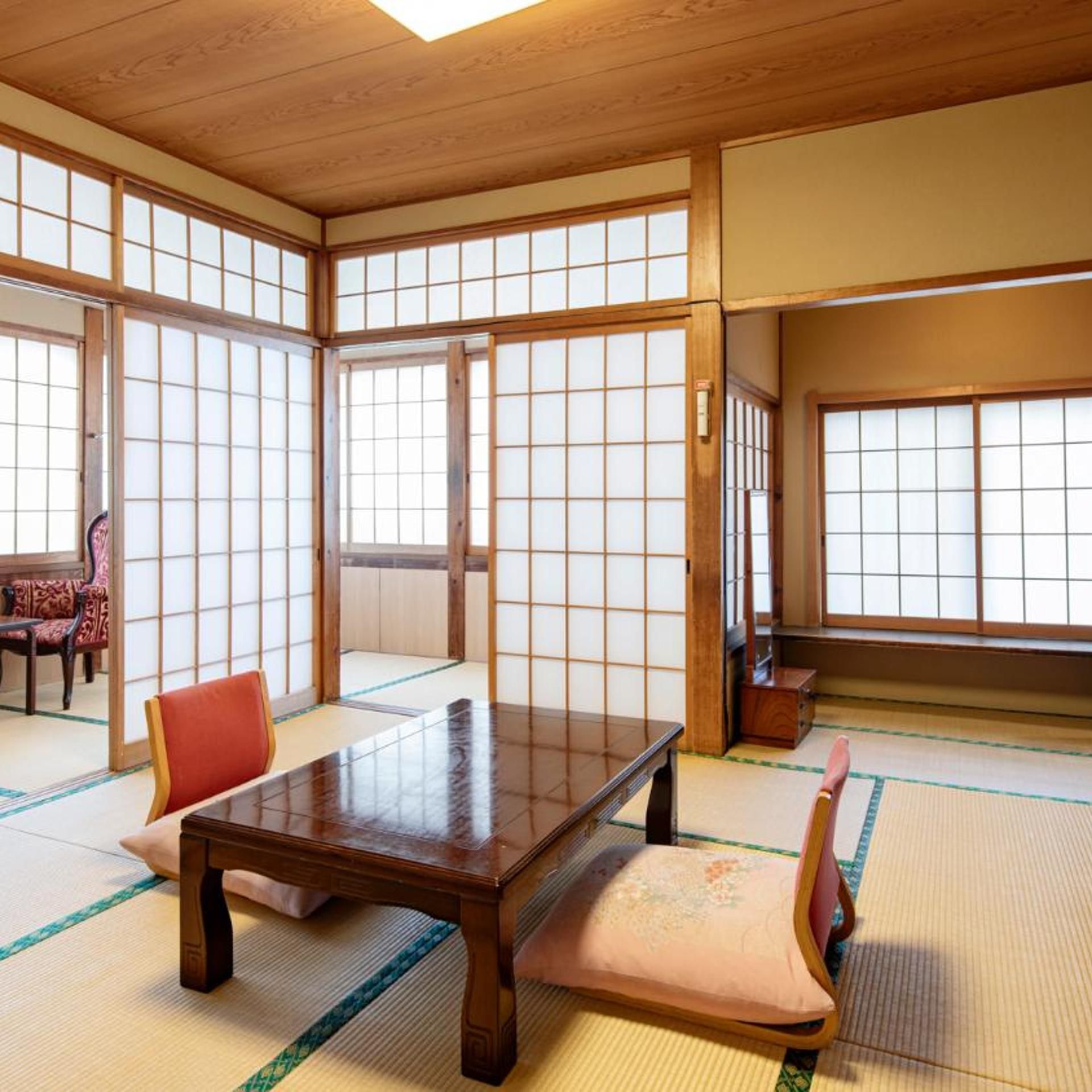 Una stanza tradizionale giapponese con pavimento in tatami, un tavolino di legno e porte scorrevoli.