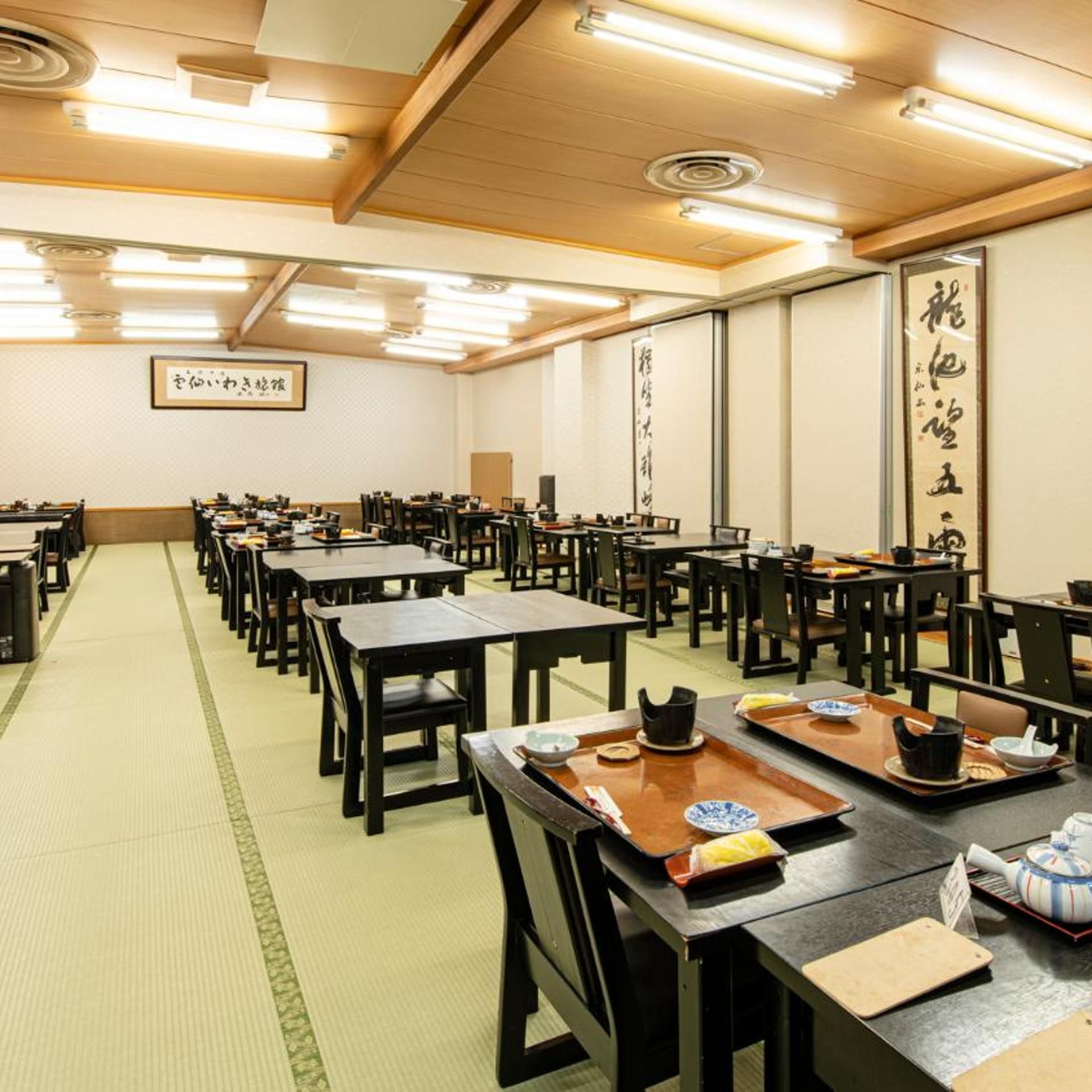 Una habitación japonesa tradicional con esteras de tatami, mesas y sillas de madera.