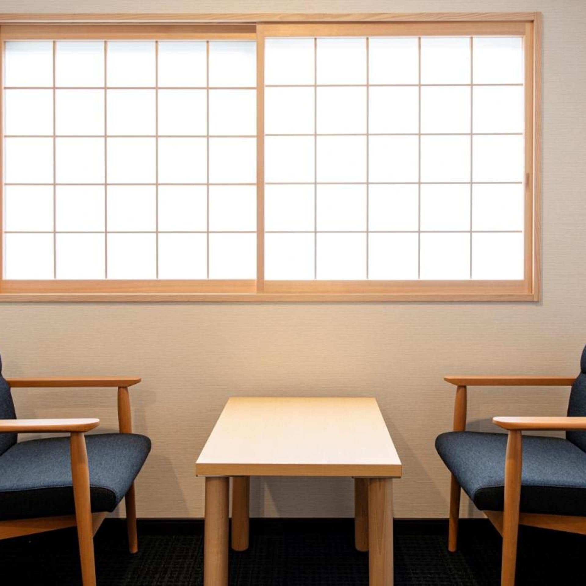 A room with a large window, two chairs, and a small table.