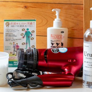 Ein roter Haartrockner, eine Handdesinfektionsmittel-Flasche und eine Schachtel mit japanischen Schriftzeichen.