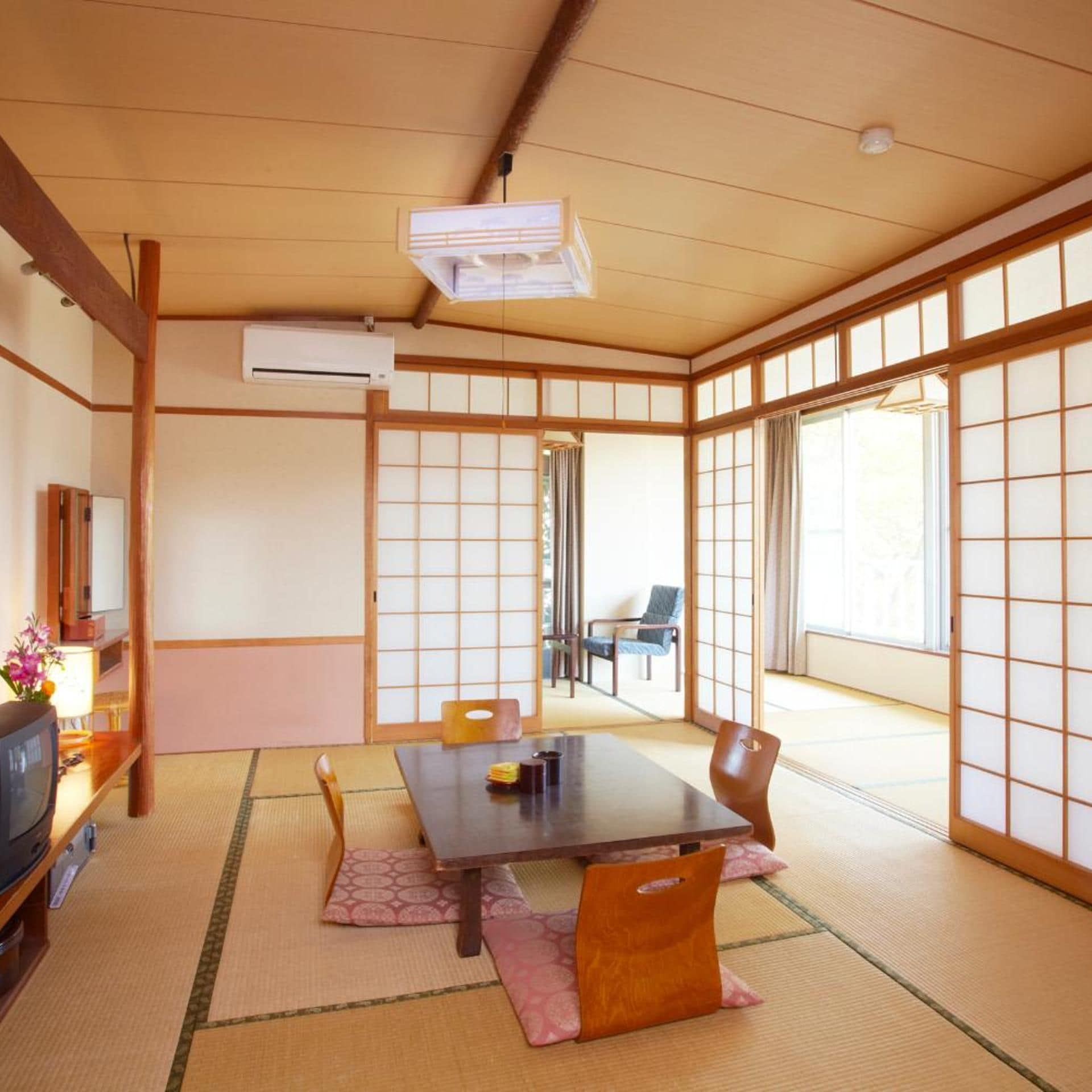 Une pièce de style japonais traditionnel, avec un sol recouvert de tatamis, une table basse et des portes coulissantes.