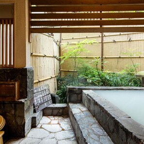 A traditional Japanese garden with a stone hot spring, bamboo fence, and a wooden structure. - Hot Springs Inn 'unzen Iwaki Ryokan' (Unzen)