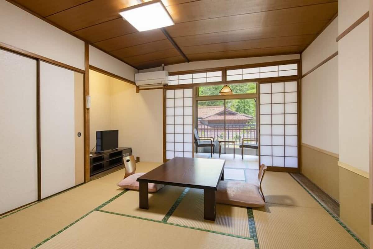 A traditional Japanese room with tatami flooring, a low table, a television, and sliding doors.