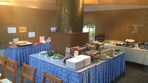 Een buffetopstelling met diverse gerechten en een grote pilaar in het midden.