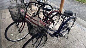 Een fiets met een mandje en een bord, geparkeerd op een betegelde vloer met patroon.