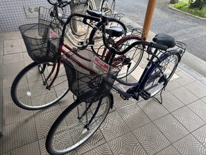 A bicycle with a basket and a sign, parked on a patterned tiled floor.