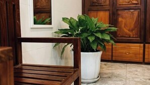 Una silla de madera, una planta en maceta y armarios de madera en una habitación.