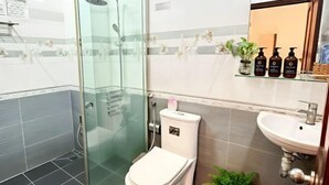 Un baño moderno con ducha acristalada, inodoro, lavabo y espejo.