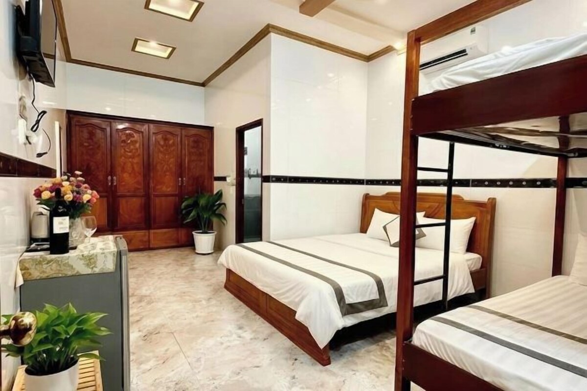 A hotel room with a bunk bed, a wooden wardrobe, a potted plant, and a marble floor.