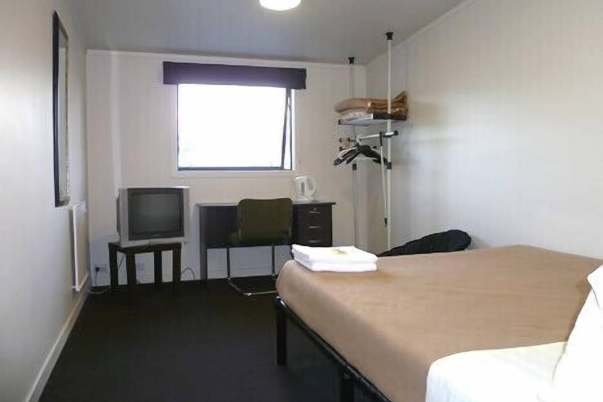 A hotel room with a bed, a desk, a chair, a television, and a window with curtains.
