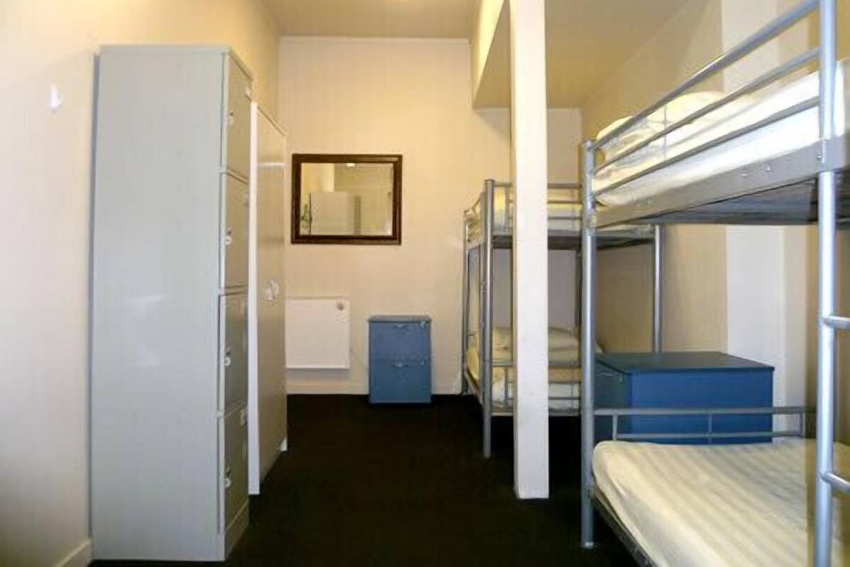 A narrow corridor with bunk beds on one side and a wardrobe on the other.