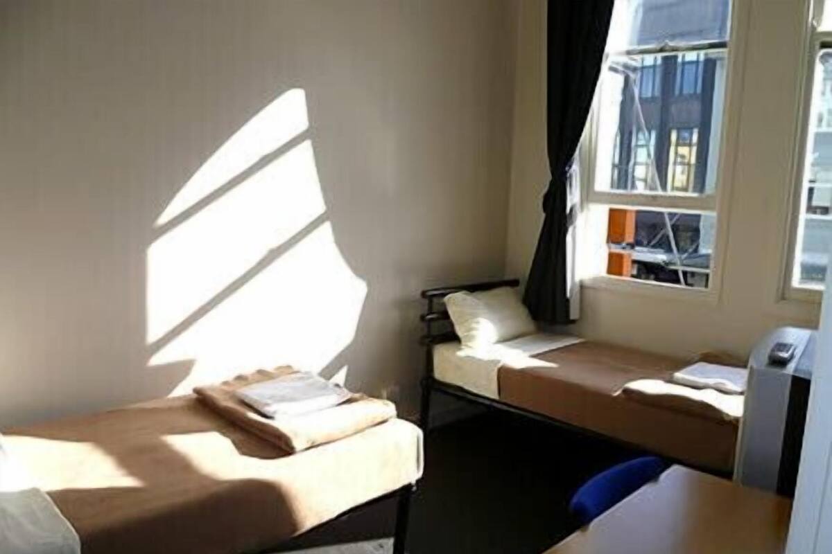 A small, single-bed room with a window, a desk, and a chair.