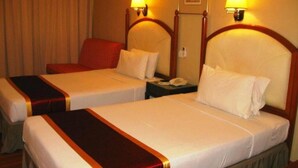 Ein Hotelzimmer mit zwei Betten, jeweils mit Kopfteil und Nachttischlampen.