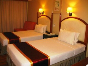 Habitación de hotel con dos camas, cada una con cabecera y lámparas de noche.