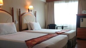 Ein Hotelzimmer mit zwei Betten, einem Schreibtisch und einem Stuhl.