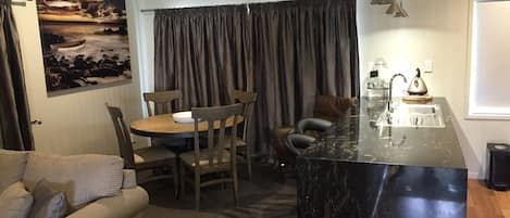 Un espacio habitable compacto con comedor, sofá, isla de cocina y un cuadro en la pared.