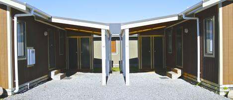 A symmetrical building with two sets of doors, a gravel ground, and a clear sky.