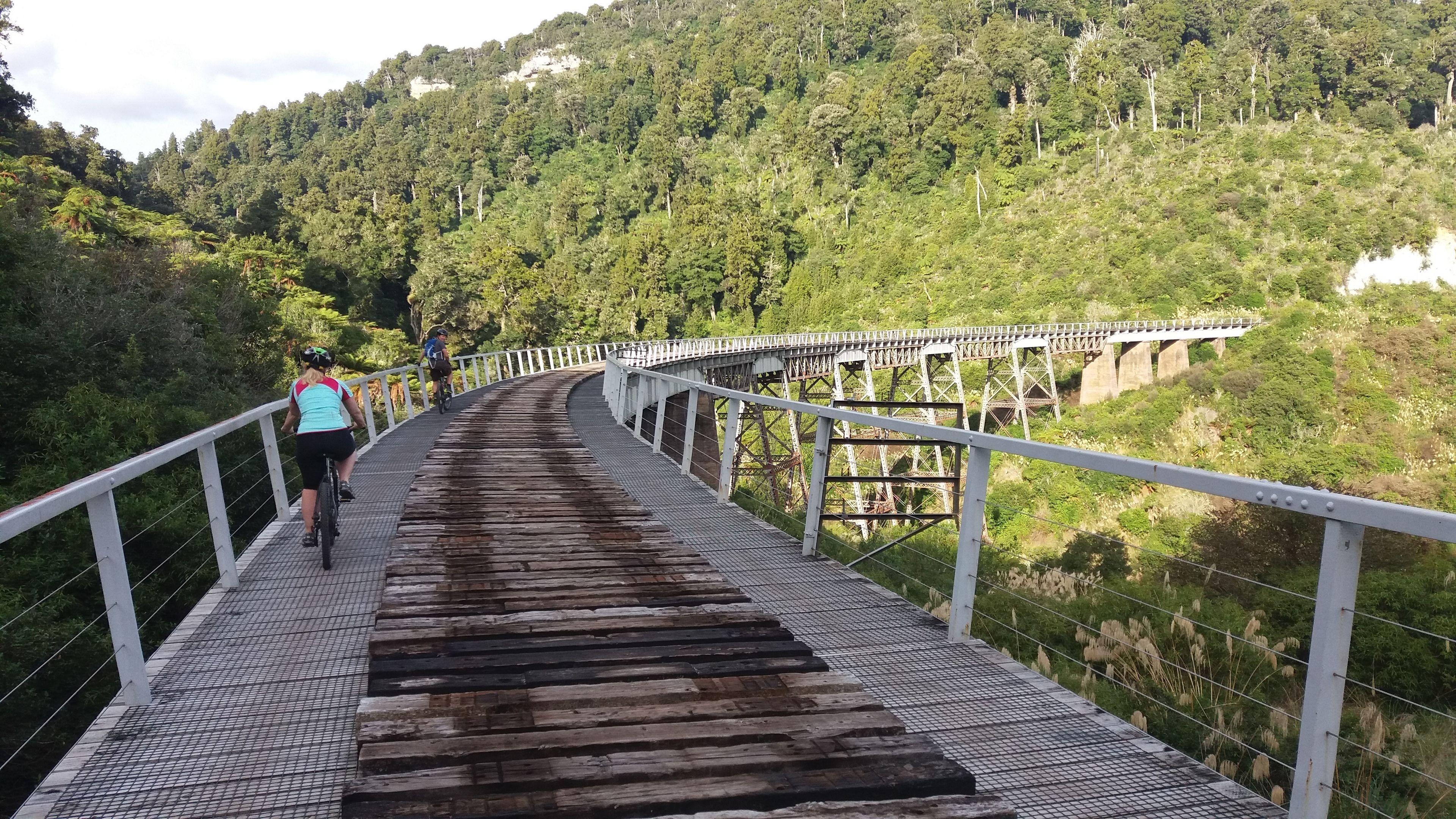 Un puente peatonal con barandillas metálicas y pasarela de madera.