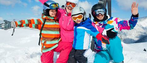 Un grupo de personas con ropa invernal colorida posando en una montaña nevada, con esquíes al fondo.