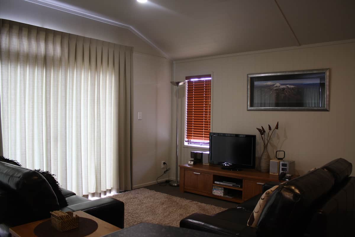 Una sala de estar con sofá, televisor y mueble de entretenimiento de madera.