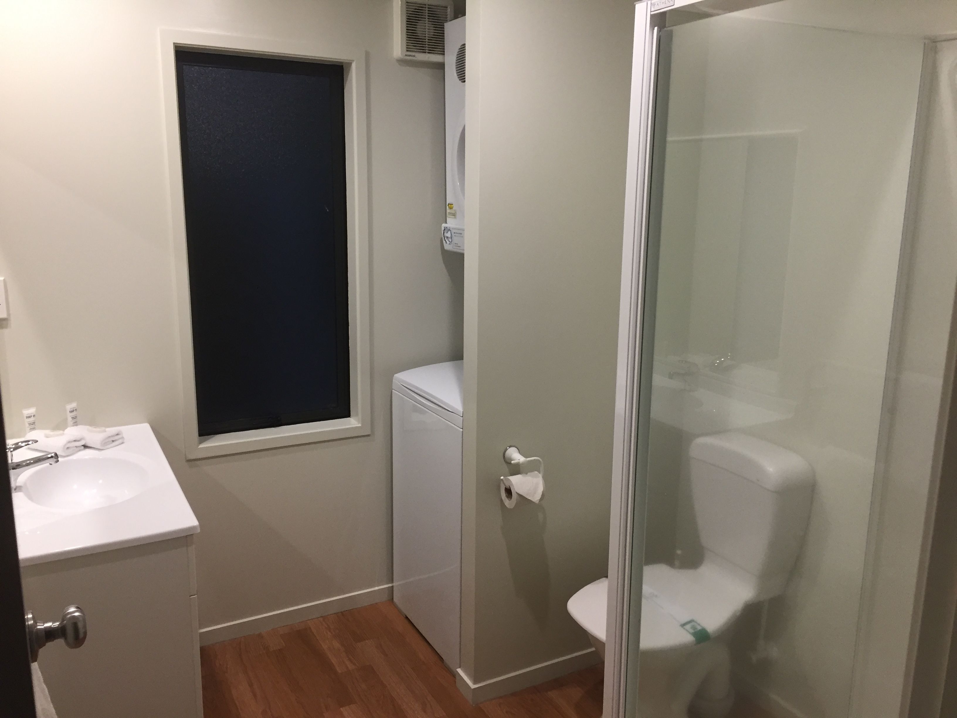 Pieni kylpyhuone, jossa on wc, pesuallas ja ikkuna.