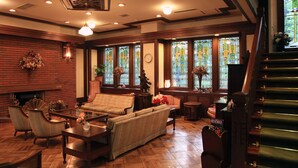 Una sala de estar acogedora con chimenea, asientos cómodos y ventanas grandes con vidrieras.