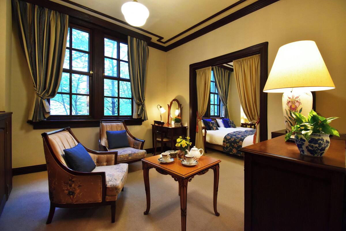 A cozy room with a sofa, armchair, and a table with a teapot and cups.