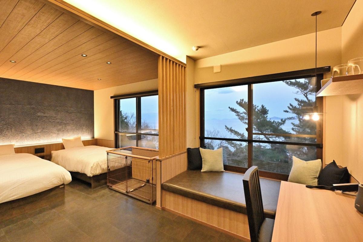 A modern hotel room with two beds, a large window with a view, and a wooden ceiling.