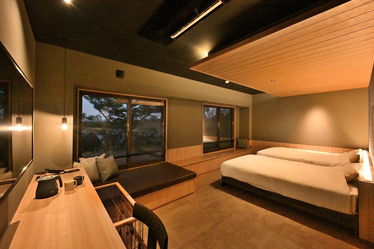 A modern bedroom with a large bed, a desk, and a seating area by the window.