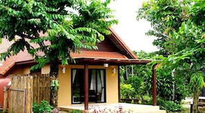 A small house with a tiled roof, a covered porch, and a window.