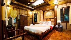 A traditional wooden room with a large bed, a wooden wardrobe, and a small table with a lamp. - Aurora Resort Chiang Dao (Chiang Dao)