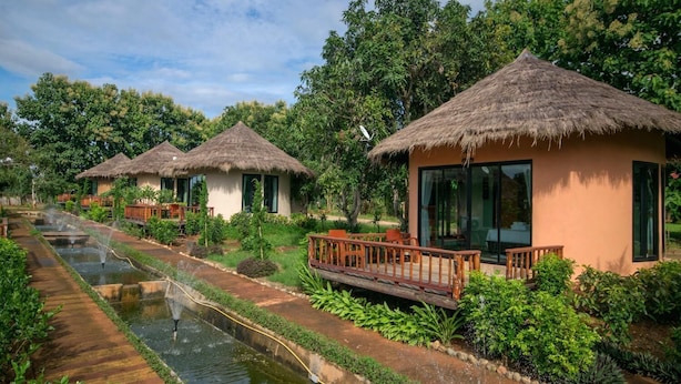 A row of thatched-roof cottages with a water channel running alongside them. - Aurora Resort Chiang Dao (Chiang Dao)
