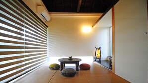 A tatami mat room with a sliding shoji screen, a small round table, and cushions. - Fu-rai-so Private Villa (Nakijin)