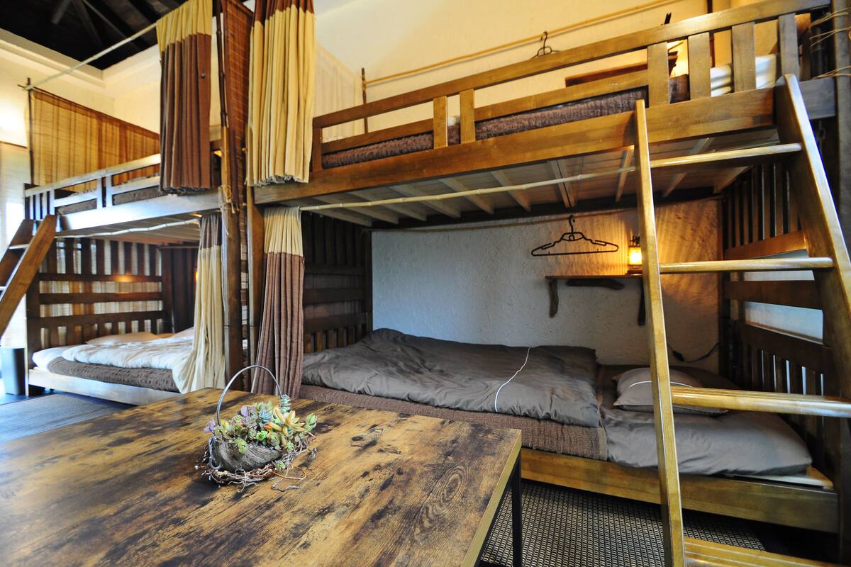 Quarto com beliche, mesa de madeira e luminária pendente.