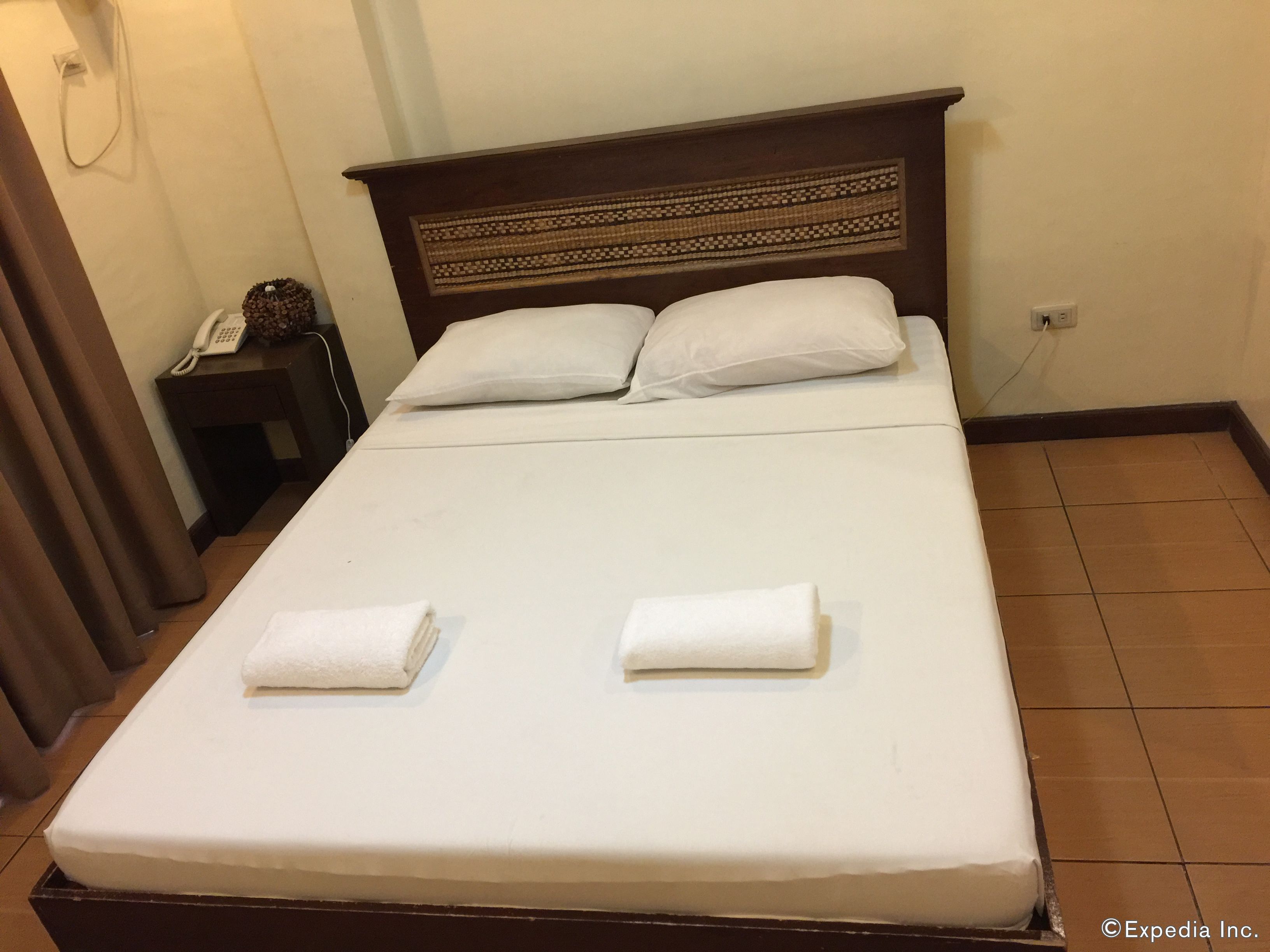 A neatly made bed with two pillows and two folded towels.