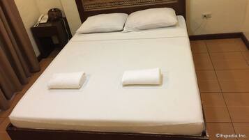 A neatly made bed with two pillows and two folded towels.