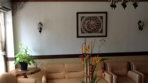 A living room with a beige sofa, a small round table with a potted plant, and a decorative vase with flowers. - Darunday Manor (Tagbilaran)