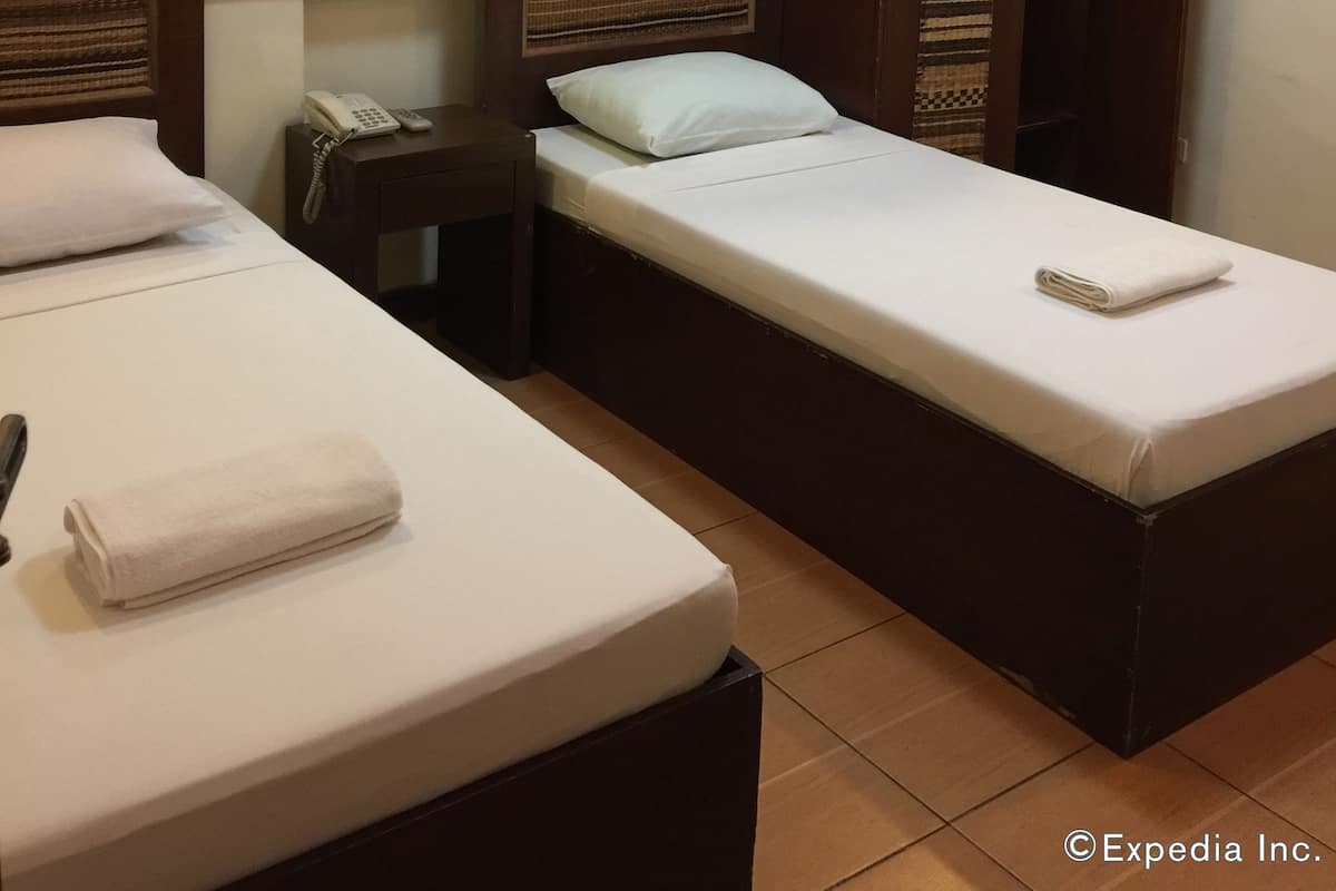 A hotel room with two single beds, a bedside table with a phone, a mirror, and a wardrobe.