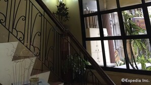 A staircase with a chandelier, a framed picture, and a view of the outside through large windows. - Darunday Manor (Tagbilaran)
